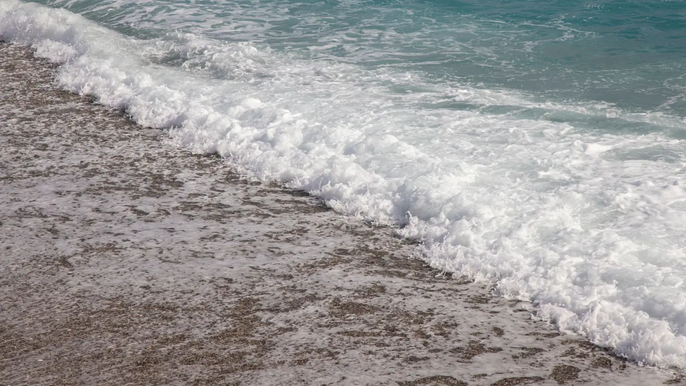 Serene ocean waves crashing on a sandy beach with clear turquoise water.