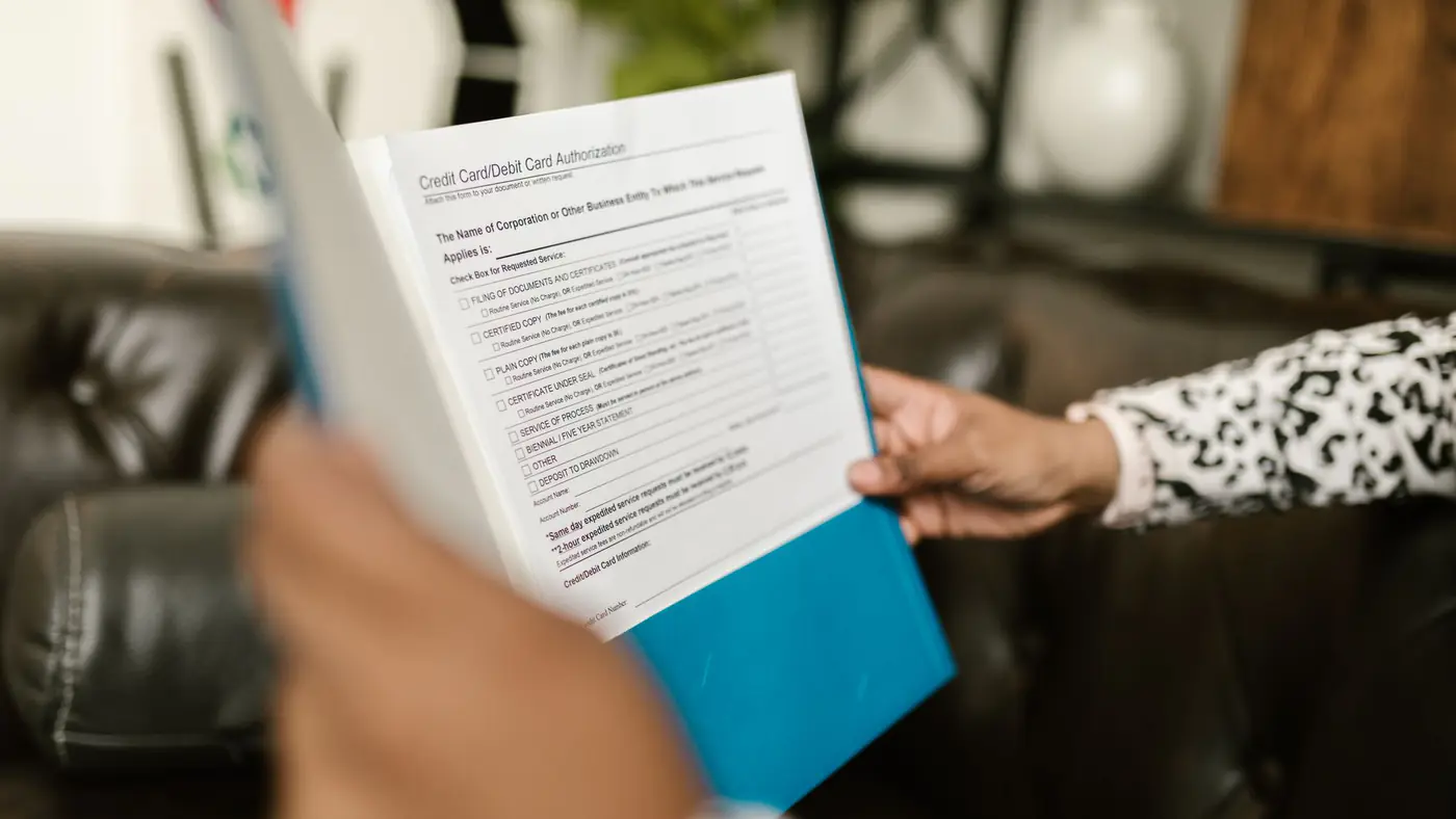Close-up of a person examining a credit card authorization form inside an office setting.