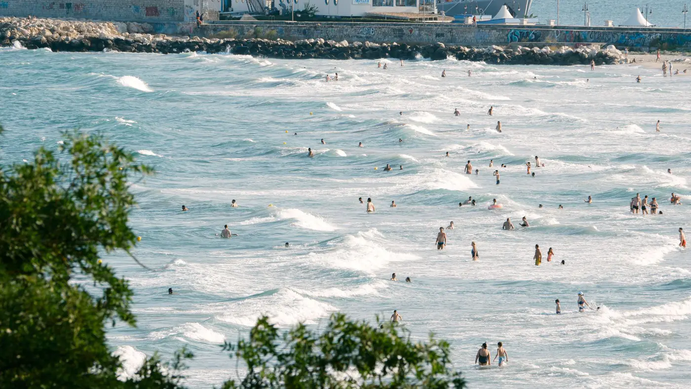 Vibrant beach scene in Bulgaria with people enjoying summer waves and a visible coastline.