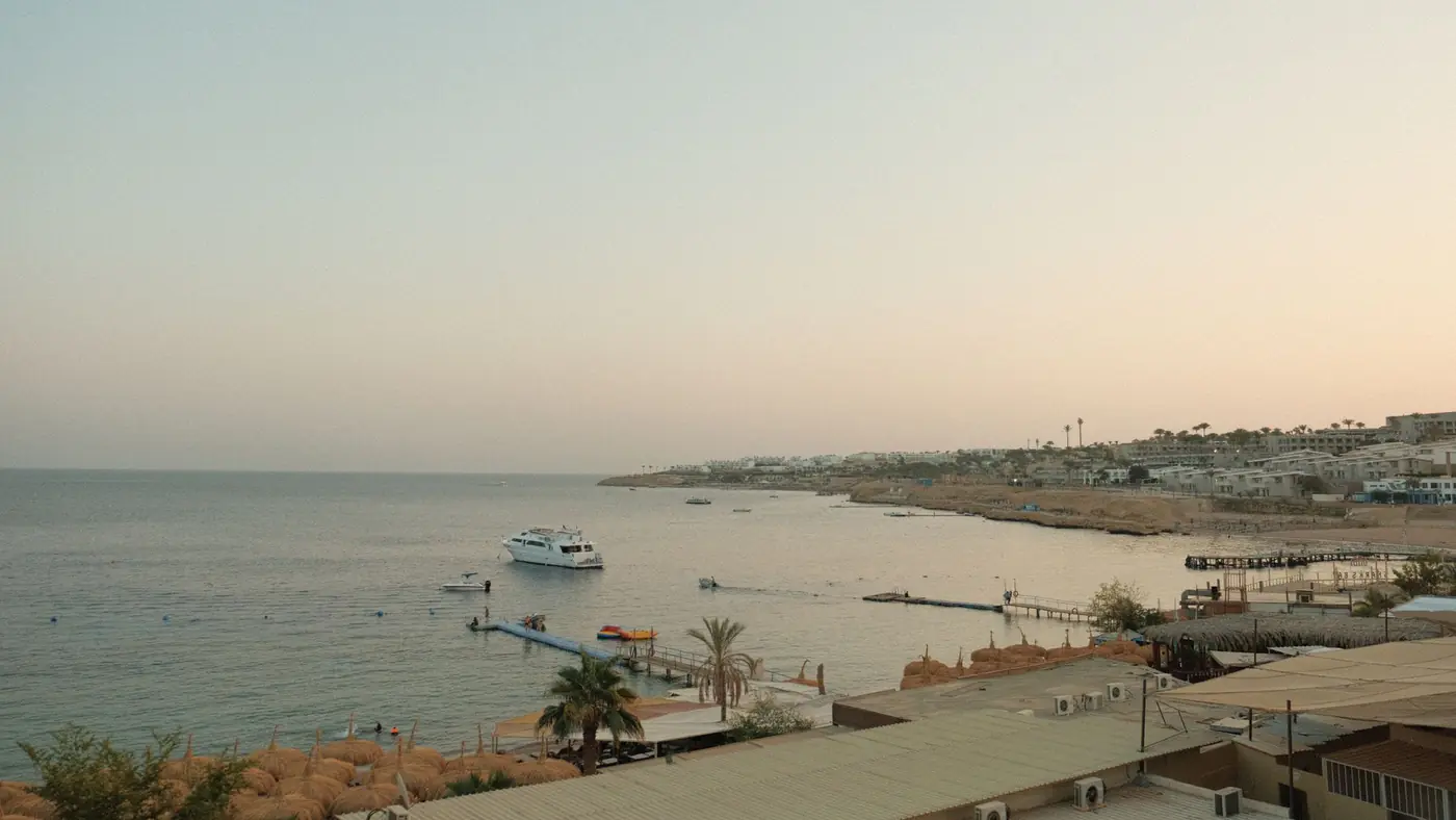 A tranquil sunset view of the Sharm El Sheikh coastline with a boat and tranquil waters.