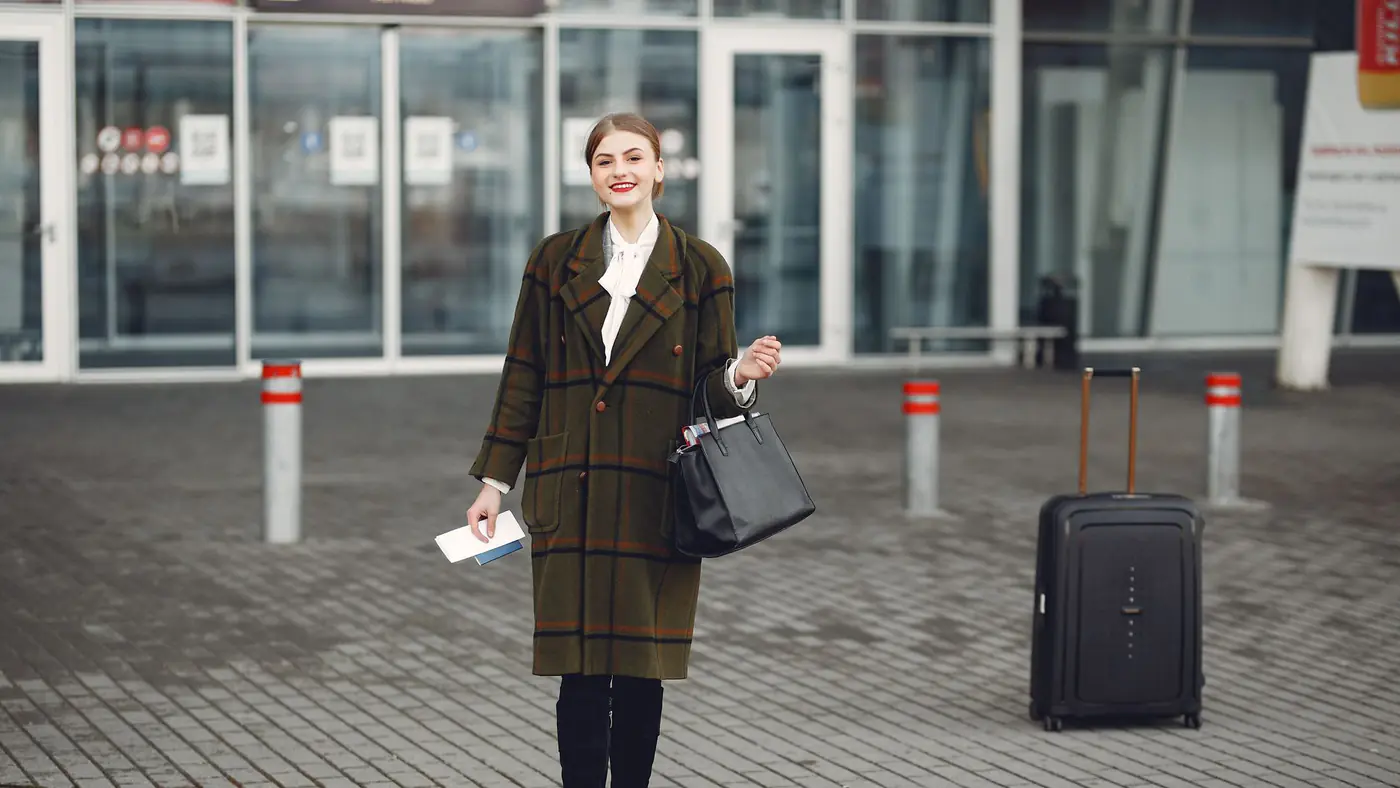 Fashionable woman with luggage arrives at airport ready for travel.