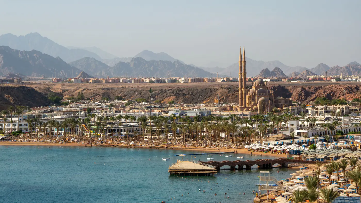 A stunning aerial view of Sharm El Sheikh featuring the coastline and city landmarks against a mountainous backdrop.