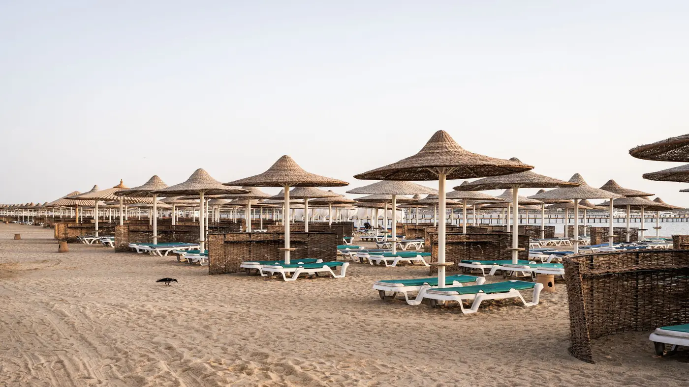 A serene view of straw sun umbrellas on the sandy beach of Hurghada, Egypt.