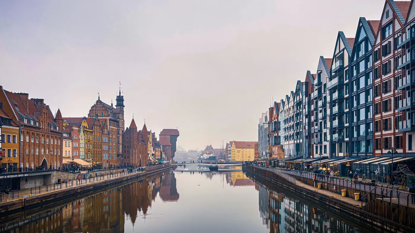 Scenic view of Gdańsk's historic architecture along the Motława River with reflections.