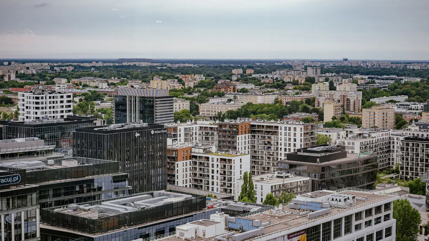 Aerial view of Warsaw showcasing modern and residential architecture against a lush backdrop.