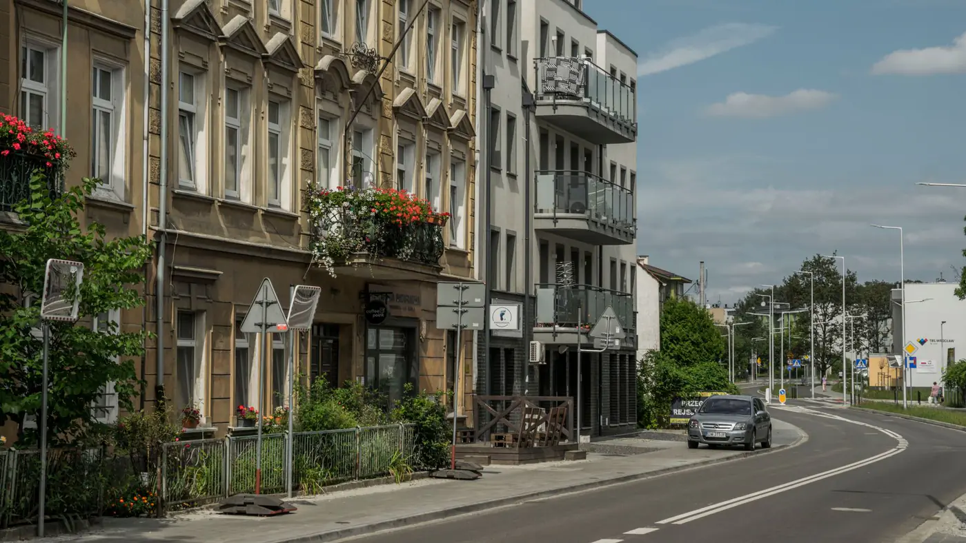 Street view of residential buildings and a car in Wrocław, showcasing city life.