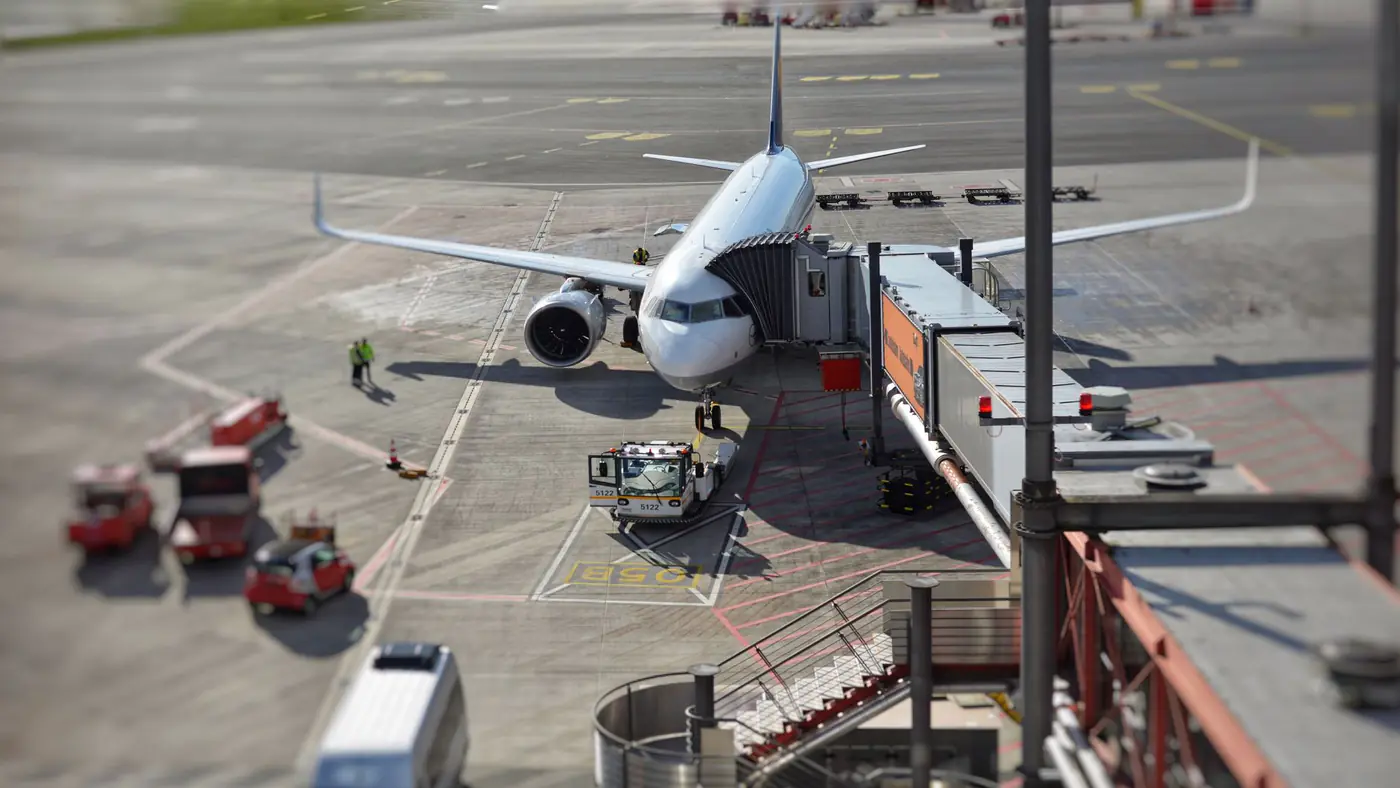 A bustling airport scene with an airplane on the tarmac being prepared for departure.