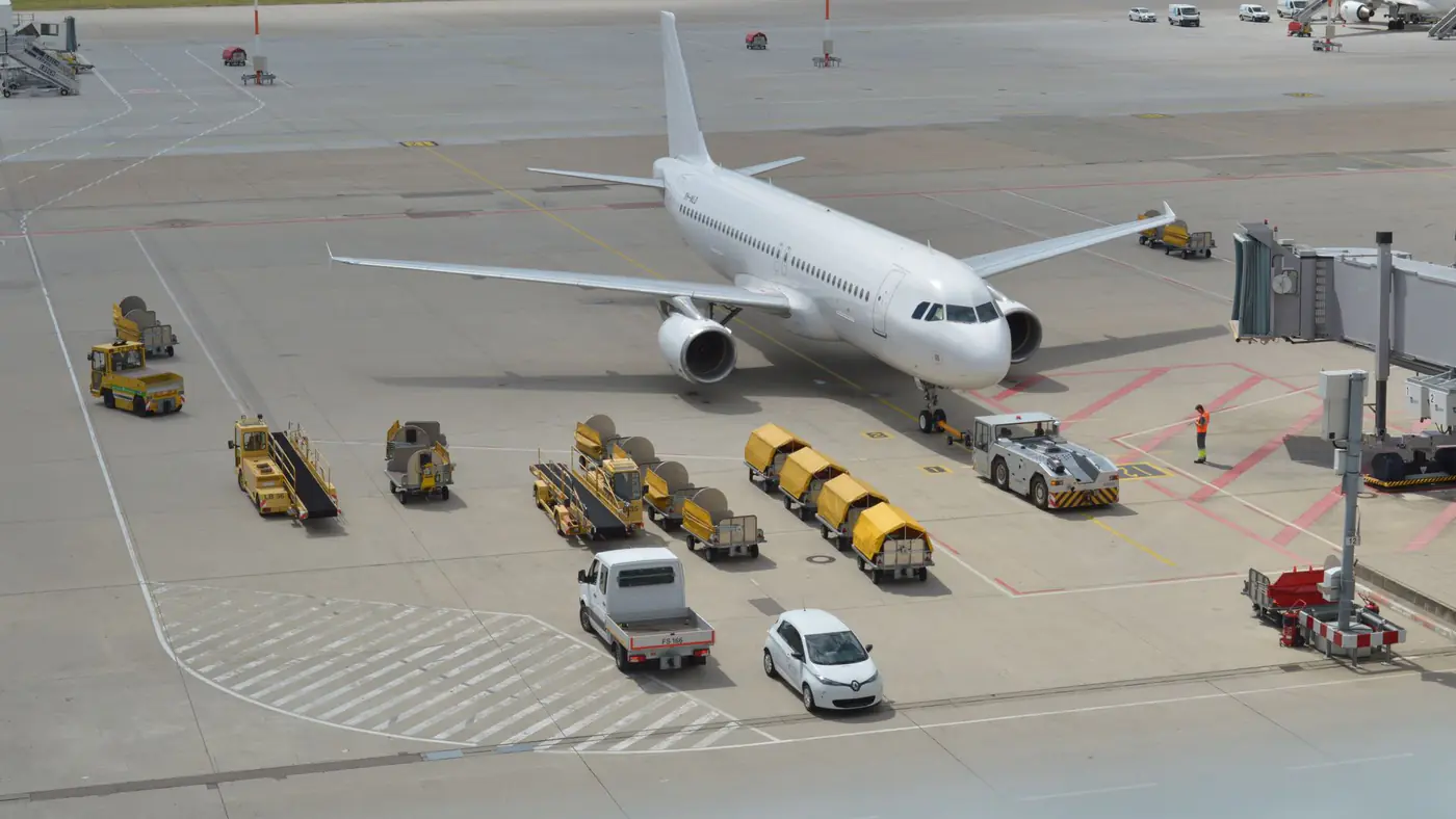 High angle view of a commercial airplane on airport tarmac with ground support vehicles.