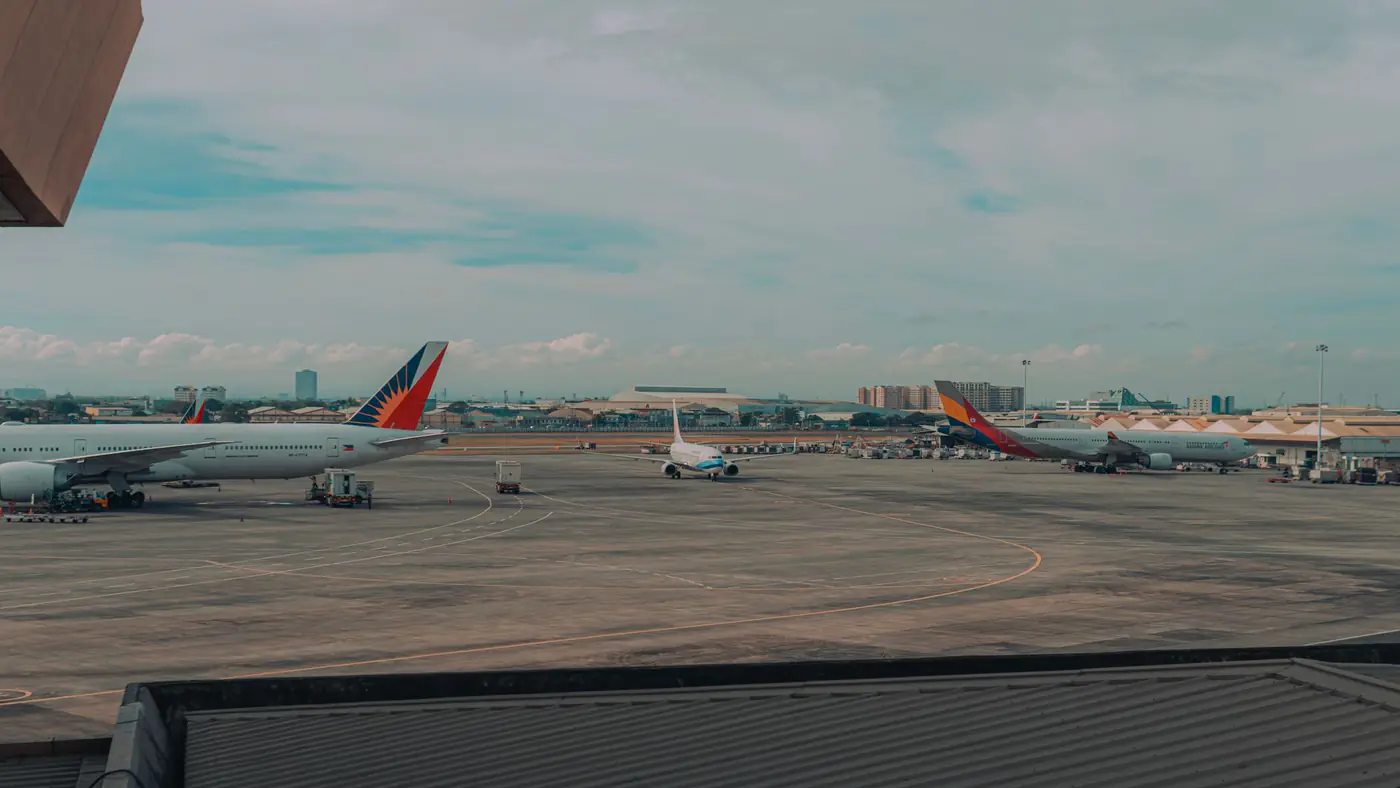 Commercial airplanes parked on an airport tarmac with a cityscape backdrop, capturing a busy travel hub.