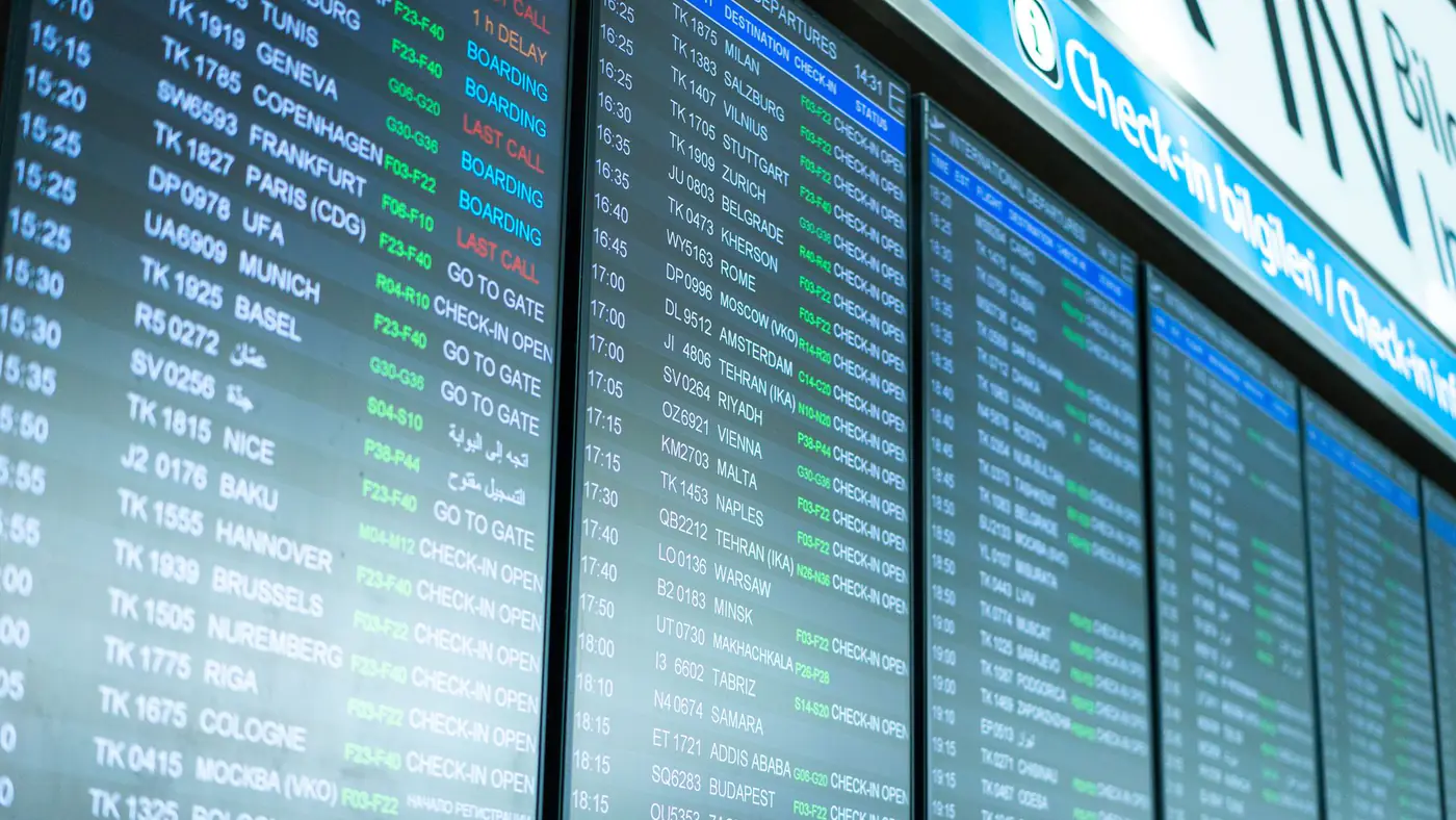 Digital screens display flight information and schedules at an airport terminal.