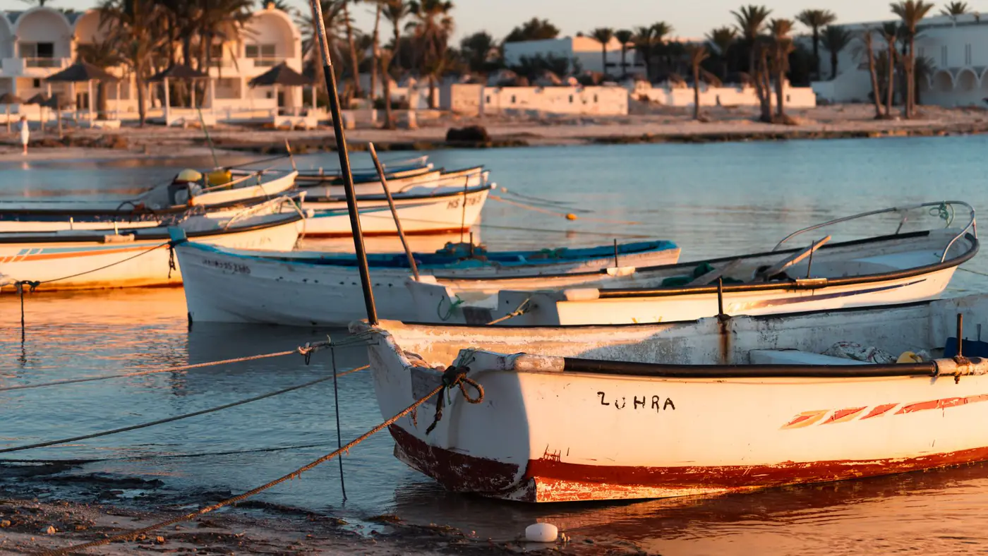 Small fishing boats anchored at sunset on the Tunisian coast, capturing a tranquil seaside scene.