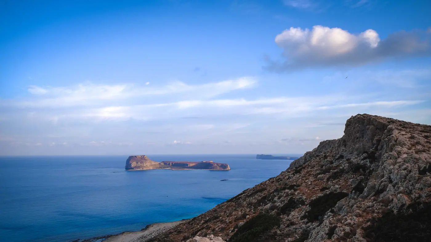 The scenic view captures a rocky coastline and serene ocean under a vibrant blue sky.